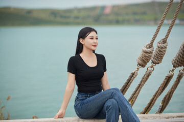 Asian woman taking photos while traveling on a wooden sailboat by the lake