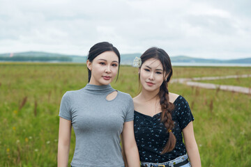 Beautiful girlfriends taking photos and playing at the bird watching platform in the grassland flower sea