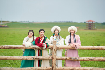 Girls wearing Tibetan costumes taking photos on the grassland