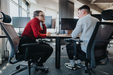 Business employees engaged in a focused conversation within a contemporary office environment. The scene captures professional interaction and collaborative teamwork in a modern workplace.