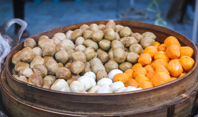 Dim Sum with various flavors cooked in a wooden steamer. Dim sum in the form of meatballs steamed in a wooden steamer