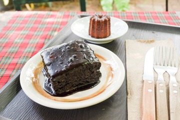 Homemade Canelés and Fudgy brownies on plate, traditional French sweet dessert,selective focus.
