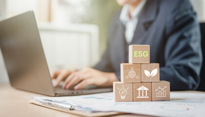 renewable, sustainability, environmental, renewable energy, climate change, communicate, community, green energy, reuse, recycle. A person is typing on a laptop with a stack of wooden blocks.