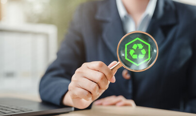 climate change, renewable energy, recycling, recycle, communicate, renewable, environmental, economy, green energy, community. A person is holding a magnifying glass over a green recycling symbol.