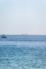 Calm blue sea with the silhouette of a large ship on the horizon