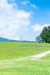 Winding path through a green grass field in hilly area  against blue sky with clouds,Pathway s curve in public park.