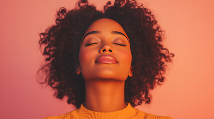 Fototapeta premium A young Black woman with voluminous curls, eyes closed, basks in warm, peachy light. Peaceful and serene.