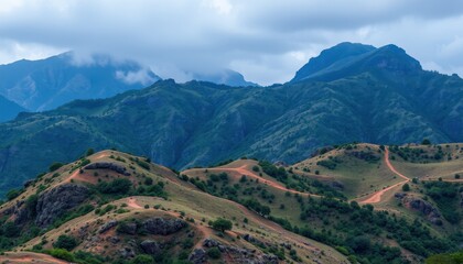 Obraz premium Rolling Hills and Distant Mountains Under a Cloudy Sky