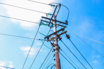 High voltage electric pole with many cables in residential area with blue sky background. The...