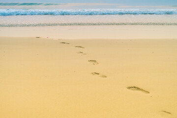 Footprints of human feet on the sand near the water on the beach.