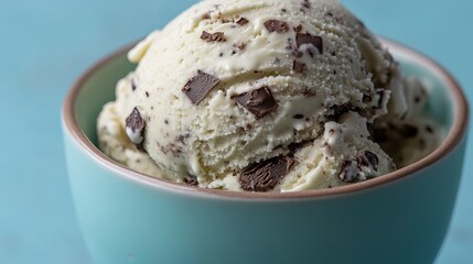 Close-up of a scoop of mint chocolate chip ice cream in a blue bowl.