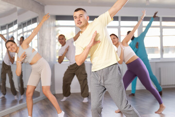 Active young man practicing hip-hop dance in training hall during dancing classes