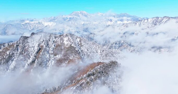 Amazing aerial landscape of winter snowy mountain with mist clouds floating in the sky at Xiling Snow Mountain of Sichuan China
