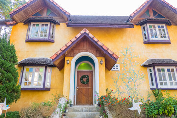 Wooden door of Yellow house with Christmas wreath.