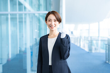 室内で手袋をつけてガッツポーズをするスーツを着た女性