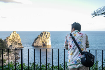 Man enjoy view of beautiful coastal cliffs faraglioni di mezzo from Giardini di Augusto in Capri,...