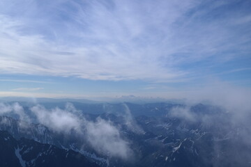 A stunning rock formation covered in snow, set against a clear blue sky with fluffy clouds in the...