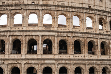 Fototapeta premium Arches archictecture of Colosseum (Colosseo) exterior with clouds and sky. Rome, Italy.
