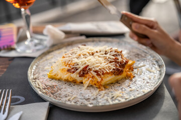 Close up freshly baked lasagna dish hand cutting.