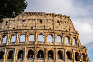 Fototapeta premium Arches archictecture of Colosseum (Colosseo) exterior with clouds and sky. Rome, Italy.