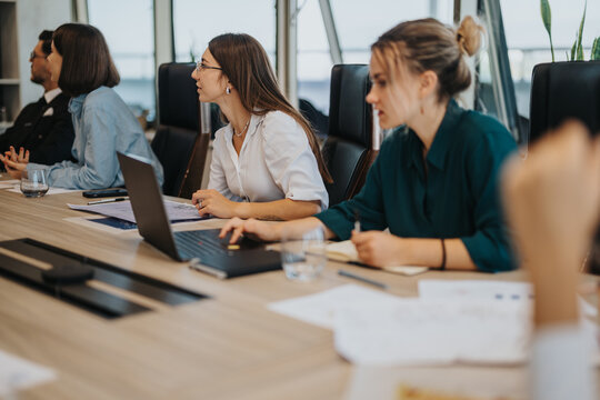 A diverse group of business people engaged in a collaborative meeting in a modern office setting, emphasizing teamwork and communication. The team is focused on discussing strategic ideas and projects