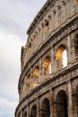 Fototapeta premium Arches archictecture of Colosseum (Colosseo) exterior with clouds and sky. Rome, Italy.