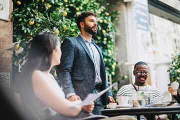 A diverse group of business professionals engaged in a strategic discussion and brainstorming session at a modern coffee bar, focusing on collaborative ideas and teamwork in an outdoor setting.