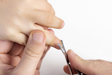 father cutting child nails. kid hand on the table and the scissors next to it along with the cut nails. worried boy with hand on head expressing pain and fear.portrait of preschooler