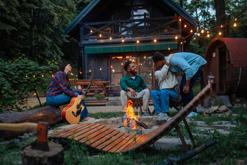 Friends enjoying a campfire in front of a cabin