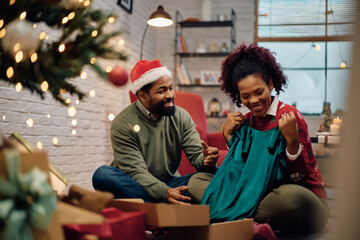 Happy African American man surprising his wife with a present for Christmas.