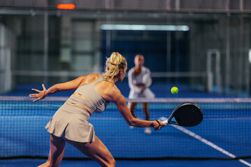 Rear view of a female padel player hitting a forehand