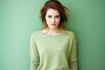 Obraz premium A woman is wearing a green sweater and standing in front of a green wall