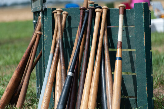 Wooden baseball bats leaning against a green crate on a sunny fi