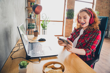 Woman enjoying video game on smartphone at home office desk