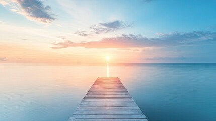 Obraz premium A peaceful scene captures a wooden pier extending into a tranquil sea, illuminated by the gentle light of a setting sun beneath a serene blue sky. Ideal for relaxation imagery with copy space.