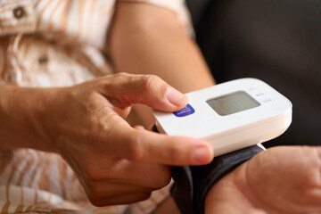 Close-up view of female hands operating a portable blood pressure monitor, assessing health status...
