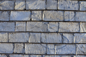 A brick wall with a lot of texture and a few scratches. The wall is gray and has a rough surface.