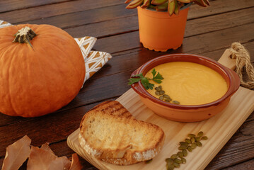 Close up view of a pumpkin soup in a bowl served with pumpkin seeds and croutons. Vegan soup. Rustic wooden background