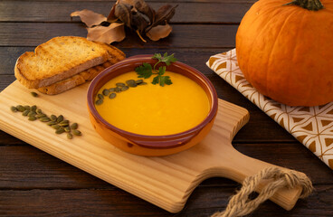 Close up view of a pumpkin soup in a bowl served with pumpkin seeds and croutons. Vegan soup. Rustic wooden background