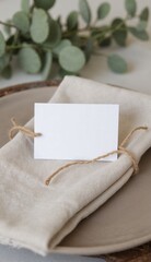 Fototapeta premium Blank wedding place card on napkin with eucalyptus decor