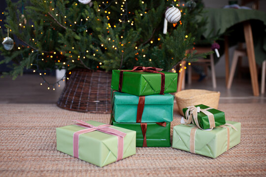 Lots of gift boxes packed in paper under the christmas tree with wicker base. Christmas, New Year concept. Selective focus.