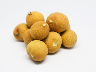 A pile, a group of fresh, ripe longans arranged beautifully in layers with inserted leaves.  Longan cut in half with seeds  Show in front of the pile.  On a white background.  Seasonal Thai fruits.