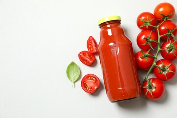 Tomato juice in a bottle and fresh tomatoes gray background 