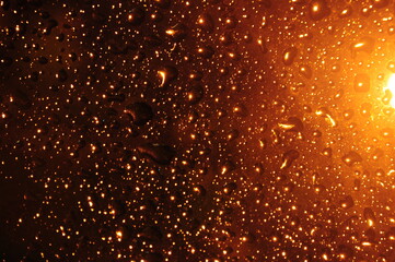 water drops on glass with golden light background
