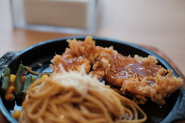 A delicious combination of crispy chicken and flavorful noodles served on a sizzling plate with vegetables