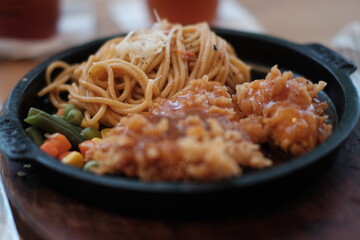 A delicious combination of crispy chicken and flavorful noodles served on a sizzling plate with vegetables