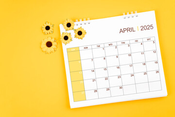 2025 April desk calendar and sunflowers on yellow background.