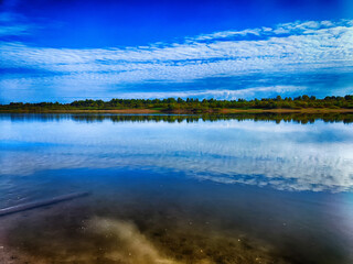 Serene riverside view reflecting the sky with gentle ripples at midday
