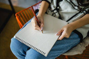 Woman sketch and draw on a blank notebook with a wooden crayon in hand