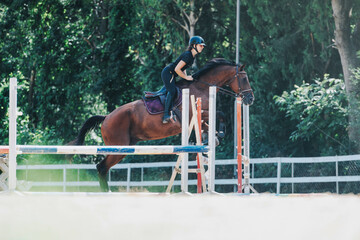 A skilled equestrian rider guides a horse over a jump in an outdoor arena, showcasing agility and...